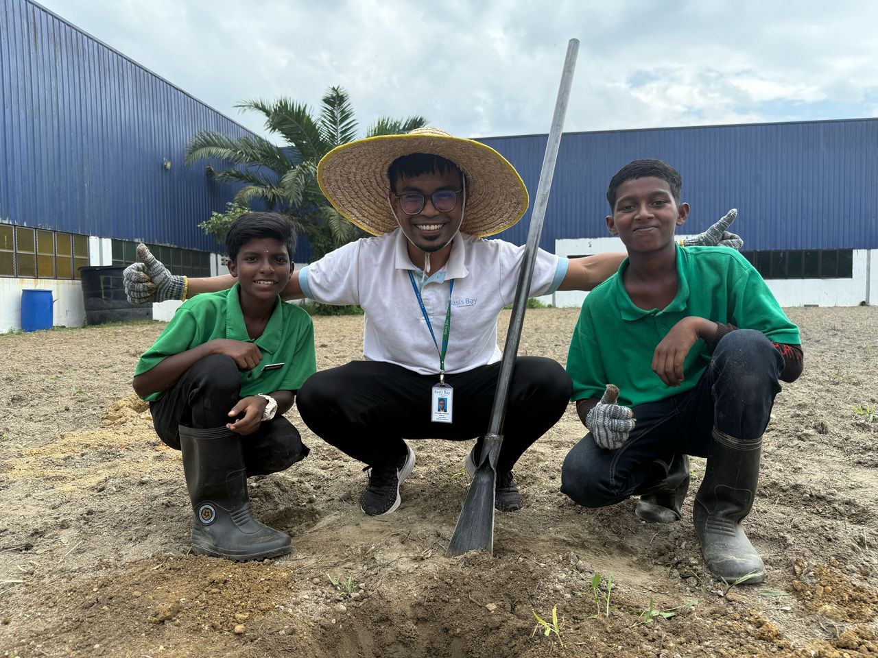 A Basis Bay volunteer and two students giving a thumbs up during a tree-planting day